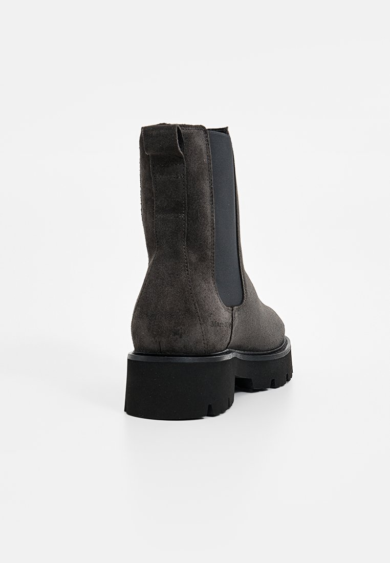 Czarne zamszowe botki za kostkę z grubą czarną podeszwą, z bocznymi elastycznymi panelami i pętelką z tyłu dla łatwego zakładania.