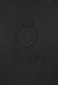 Svart sweatshirt med en texturerad BVB-logotyp och två stjärnor ovanför. Har en upphöjd Puma-logotyp längst ner, allt i svart. Mjuk tyg.