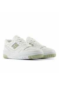 White leather sneakers with green accents, perforated detailing, and a low-top design. Features a textured rubber outsole and laces.