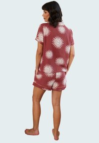 Red cotton shorts and short-sleeve shirt set featuring a sun print in white. Shirt has a collar and pockets; shorts have rolled cuffs.