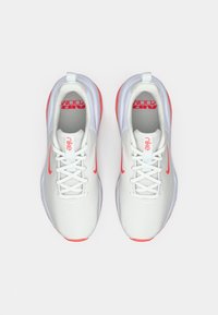 Ζευγάρι λευκών και κόκκινων αθλητικών παπουτσιών Nike Air Zoom με κορδόνια, καταγεγραμμένο από πάνω σε λευκό φόντο.