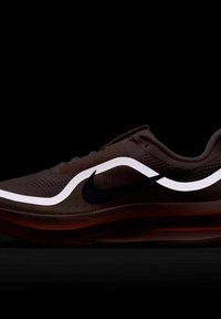 Zapatilla deportiva oscura con el logo de Nike en negro y un diseño de ola blanca reflectante a lo largo del costado, sobre un fondo negro.
