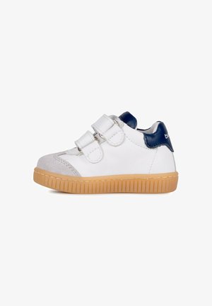 Scarpa bianca per bambino piccolo con due cinturini in velcro, puntale grigio, toppa sul tallone blu navy e suola in gomma marrone chiaro.