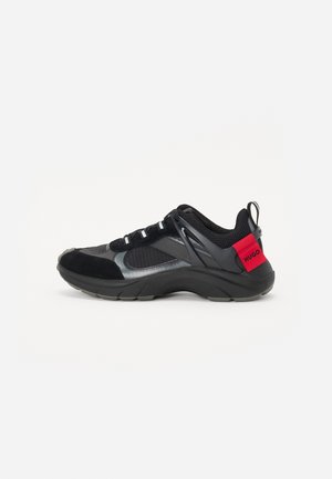 Chaussure de sport noire en mesh et suède, au design élégant, avec des semelles en caoutchouc et une étiquette rouge distinctive au talon.