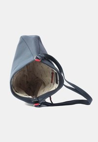 Leren schoudertas in marineblauw met een taps toelopend ontwerp, voorzien van een gevoerde binnenkant met geometrische patronen en een klein ritszakje.