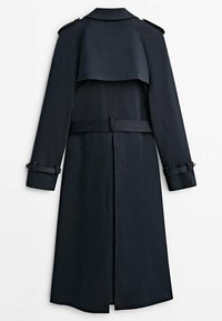 Long trench-coat bleu marine foncé avec empiècement au dos, taille ceinturée, épaulettes et sangles aux poignets, vu de dos.