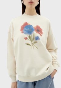 Crème sweatshirt met bloemenprint in blauw en rood. Voorzien van een ronde hals, lange mouwen en geribde manchetten. Zacht, gestructureerd materiaal.