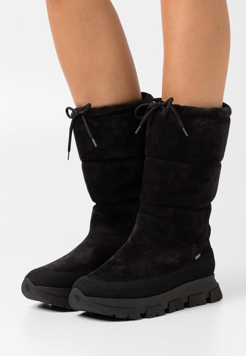 Botines de ante negro con un diseño acolchado, punta redonda, detalles de cordones y una suela de goma gruesa y texturizada.