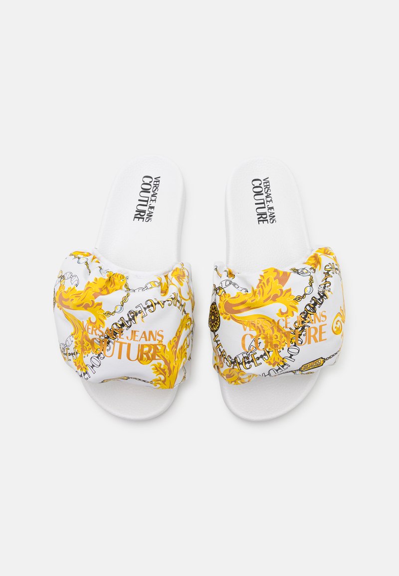 Witte slip-on sandalen met een gepolsterde bovenkant met een gele en zwarte Barokprint. Inclusief de tekst "Versace Jeans Couture" in een vet lettertype.