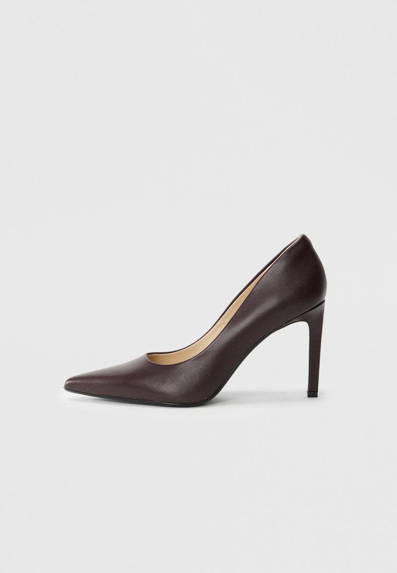 Scarpa con tacco alto a punta in pelle marrone scuro con tacco a stiletto sottile, mostrata di lato su uno sfondo bianco.