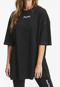 T-shirt nera oversize in cotone con maniche corte. Presenta un logo "PUMA" ricamato in bianco sul petto.