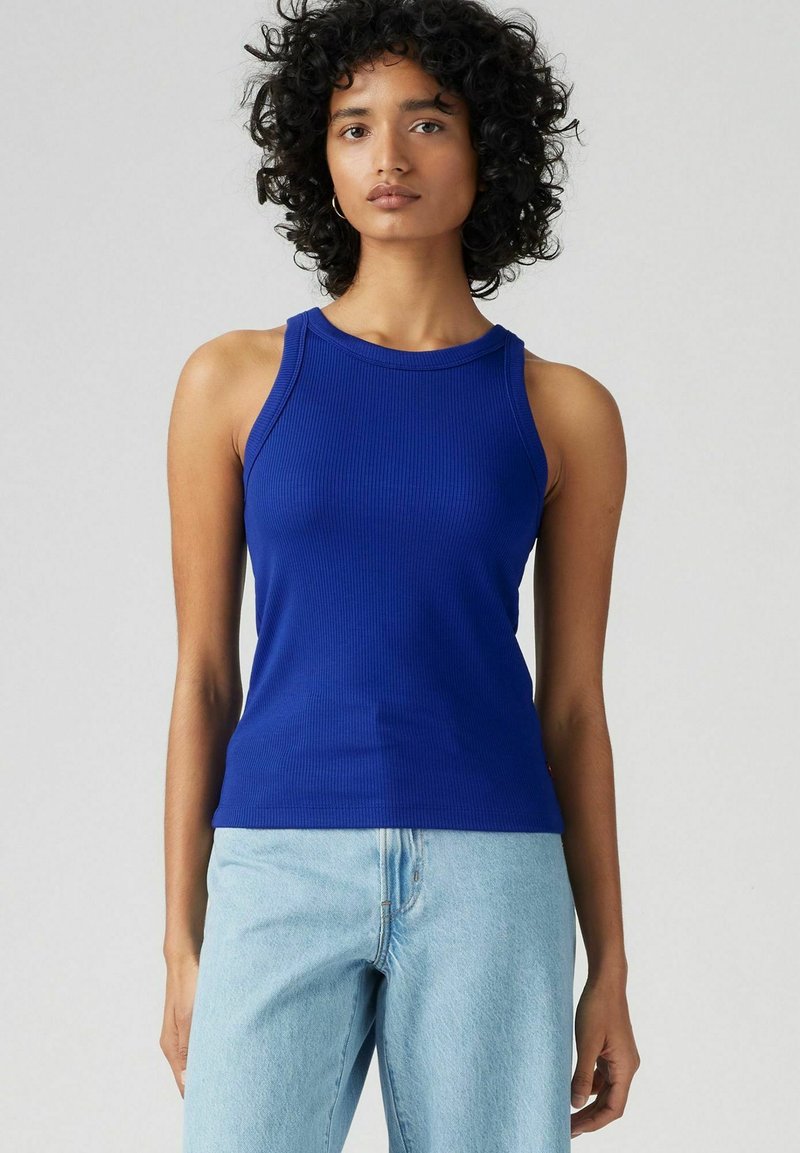 Canotta a coste blu navy con scollatura rotonda e spalline larghe, abbinata a jeans azzurri. Tessuto morbido, design aderente.