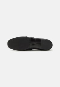 Talpă de pantof din piele neagră, cu o suprafață netedă, vârf rotund, profil minim de aderentă și un branding subtil pe lateral.