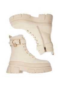 Beżowe wojskowe buty z eko skóry z grubymi, masywnymi podeszwami, sznurowaniem z przodu, zamkiem błyskawicznym po boku oraz ozdobnym paskiem na kostkę z złotą klamrą.