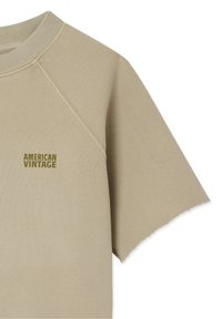 Sweat-shirt beige à manches courtes en coton, avec un col ras du cou côtelé et un ourlet droit à bord brut. Logo "AMERICAN VINTAGE" en vert foncé.
