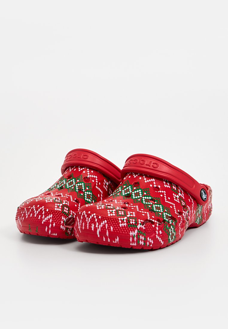 Zoccoli rossi con un motivo geometrico natalizio in verde e bianco. Realizzati in materiale leggero con fori di ventilazione e cinturino regolabile.