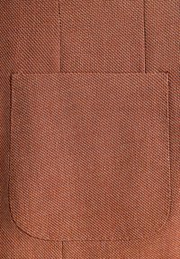 Brązowa tkanina teksturowa ma prostokątną kieszeń, przeszyte krawędzie oraz subtelny wzór tkany, co tworzy trwały i praktyczny design.