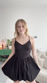 Juodas suknelė su prigludusia griovelio formos liemene ir plačiu, susiraukšlėjusiu sijonu. Su plonomis reguliuojamomis petnešėlėmis ir lygiu tekstūru.