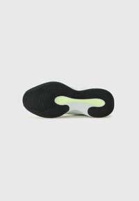Semelle en caoutchouc noir avec un motif de semelle élaboré, dotée d'un insert blanc et vert clair. Texture lisse et design courbé indiquent un style athlétique.