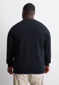 Schwarzer gestrickter Pullover, lange Ärmel, gerippter Halsausschnitt und Bündchen, strukturiertes Muster, lockere Passform, sichtbare Nähte auf dem Rücken.