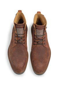 Bottes de cheville en cuir brun avec une finition légèrement usée, bout rond et lacets bruns. Présente une couture minimaliste et un doublure intérieure beige.