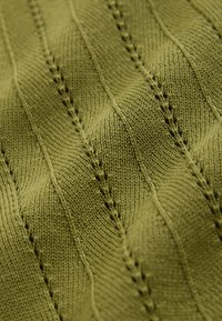 Tissu tricoté vert olive avec un motif texturé de lignes en zigzag verticales et de petits trous dans un design répétitif.