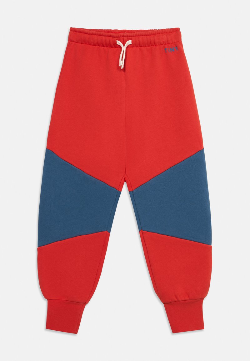 Pantalon de survêtement rouge avec des renforts bleus aux genoux, taille élastique avec cordon blanc et chevilles resserrées.