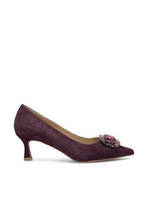Pump in suede viola con punta appuntita e una decorazione di gioielli sul pannello centrale. Presenta un tacco basso e svasato per maggiore stabilità.