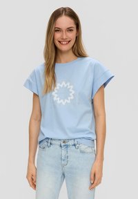 Lichtblauwe T-shirt met korte mouwen, voorzien van een cirkelvormige witte grafiek en tekst in een casual lettertype, gemaakt van zachte stof.