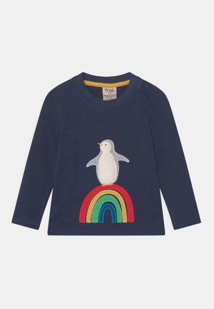 T-shirt bébé bleu marine à manches longues avec un pingouin blanc debout sur un arc-en-ciel coloré brodé sur le devant.