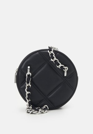 Sac à main rond noir matelassé avec une bandoulière chaîne argentée sur fond blanc.