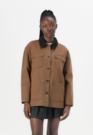 Veste en toile marron avec un col en velours côtelé, deux poches avant et des boutons. Le design se caractérise par une coupe ample et une silhouette structurée.