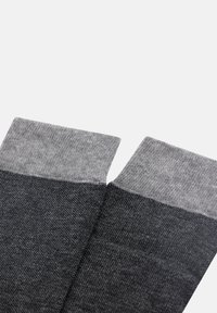 Šedé ponožky s tmavě šedým tělem a světle šedými elastickými manžetami. Textura se jeví jako hladká; látka vykazuje jemný tkaný vzor.