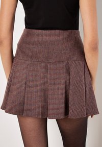Karierten Rock in dunklen Rot- und lila Tönen, mit einem ausgestellten Design, Falten und einem anliegenden Bund. Ideal für Freizeitkleidung.