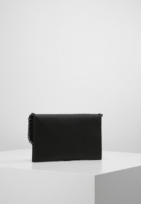 Clutch bag in ecopelle nera con forma rettangolare e tracolla in catena. Texture liscia, chiusura con zip e design minimalista.