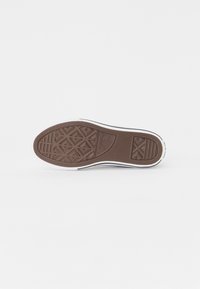 Semelle de chaussure en caoutchouc marron, affichant des motifs de semelle géométriques, un logo en relief et des détails en bordure blanche. Texture lisse et durable.