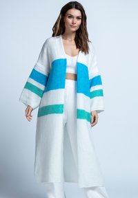 Biały sweter dziergany z szerokimi rękawami, z poziomymi paskami w jasnoniebieskim, zielonym i ciemniejszym niebieskim kolorze. Miękka tekstura i otwarty krój z przodu.