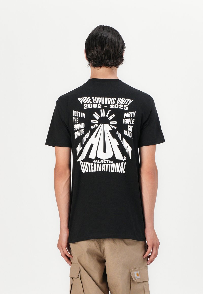 Zwarte katoenen T-shirt met gedurfde witte grafische tekst op de achterkant. De tekst bevat "Zomer van 2002-2025" met een centraal logo-ontwerp.