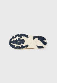 Rubber sneaker outsole with a patterned tread, featuring navy blue and cream colors, highlighting textured grips and a durable design.