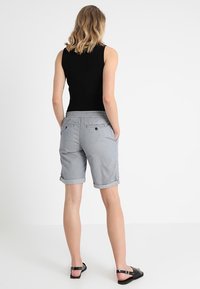 Szare szorty z zawiniętym dołem, wykonane z lekkiego materiału. Posiadają dwie tylne kieszenie z guzikami oraz elastyczny pas.