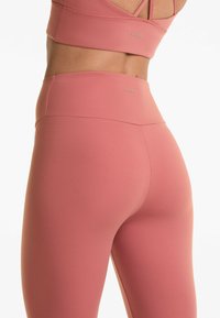 Högmidjade, sömlösa rosa leggings tillverkade av stretchigt material med en mjuk textur, med en subtil logotyp för varumärket på midjebandet.