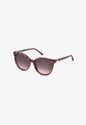 Lunettes de soleil œil-de-chat en écaille marron avec des verres teintés foncés et des branches fines sur fond blanc.