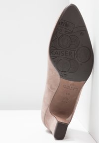 Semelle de chaussure en daim à bout pointu avec motifs de pièces embossés, texte « KAISER », marque Peter Kaiser et un petit talon carré.