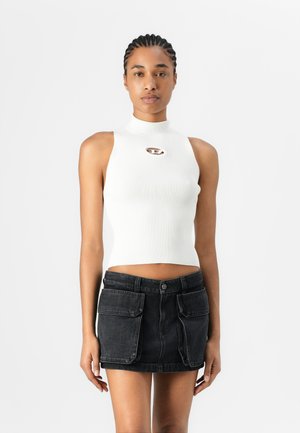 Witte geribbelde halter crop top met een uitsnijding aan de voorkant, gecombineerd met een zwarte denim mini-jurk met twee voorzakken en een knoopsluiting.