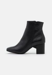 Botas negras hasta el tobillo con punta afilada, hechas de cuero sintético texturizado que imita la piel de cocodrilo, con un tacón cuadrado grueso.