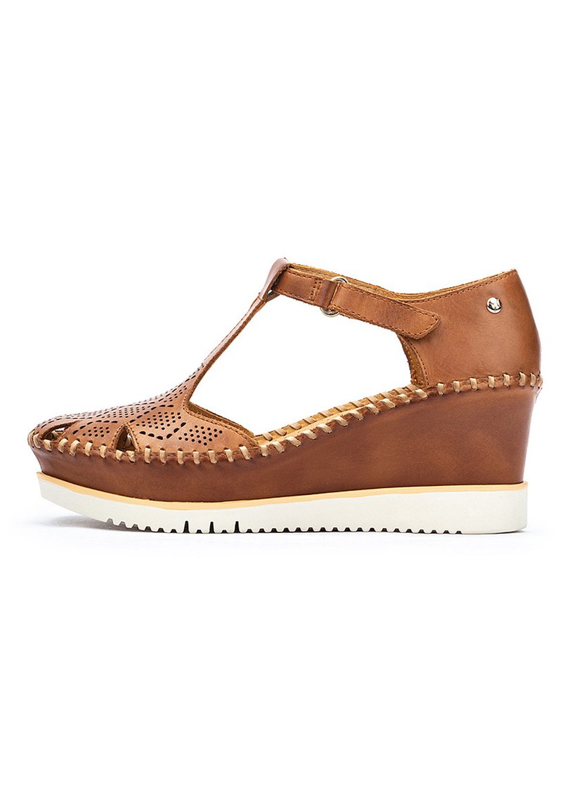 Scarpe con tacco a zeppa in pelle marrone, con parte superiore perforata, design a T-strap e suola in gomma bianca. Presentano cuciture decorative lungo i bordi.