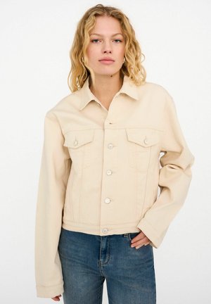 Béžová rifľová bunda s golierom, dvoma náprsnými vreckami, striebornými gombíkmi a skráteným strihom. Hladká textúra s viditeľnými švami.