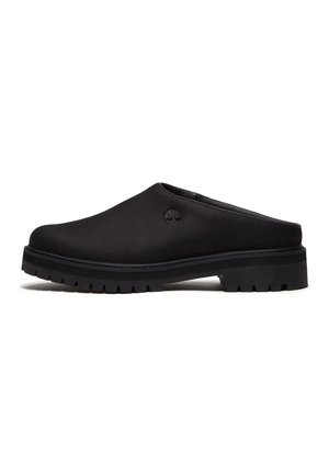 Sort mule-slip-on sko med tyk sål med gribemønster og lille trælogo på siden, vist fra ydersiden på hvid baggrund.