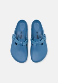 Zuecos de goma azules con un acabado suave, que presentan detalles de hebilla en los laterales y un diseño de parte trasera abierta. Dos agujeros de ventilación a cada lado. Talla 45.