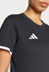 Μαύρο αθλητ ικό μπλουζάκι από βαμβάκι, με λευκή αντίθεση στα μανίκια και μικρό λευκό λογότυπο στο στήθος. Μανίκια κοντά, στρογγυλή λαιμόκοψη.